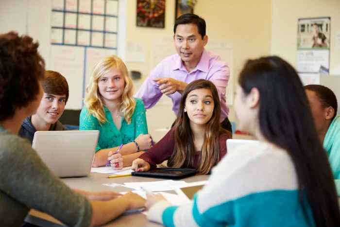 Students sitting at a table with a coach assisting them.